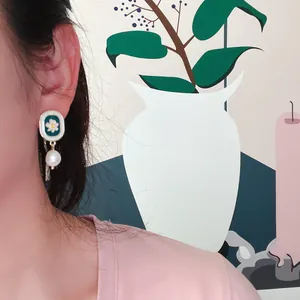 Gros plan sur les boucles d'oreilles vintage en émail marguerite et perle baroque