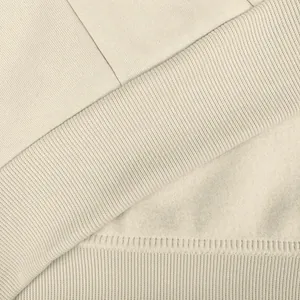 Detalle de primer plano de sudadera con capucha de felpa beige con dobladillo acanalado