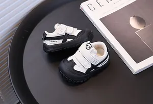 Close-up of black and white toddler walking shoes with panda logo and velcro straps.