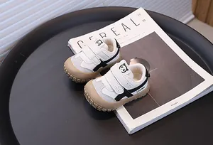 Detailed view of white baby sneakers featuring panda logo and protective tan toe caps