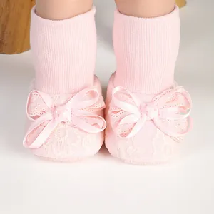 Detailed view of pink baby girl socks with elegant lace patterns and satin ribbon bows.