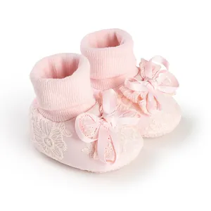 Close-up of pink baby girl socks with delicate lace floral embroidery and satin bow detail