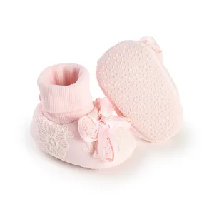 Close-up of pink baby socks with lace floral pattern and bow accent on white background