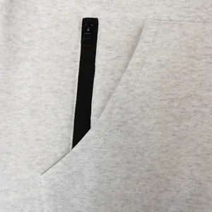 Primer plano del detalle de la cremallera negra y el bolsillo en una sudadera gris.