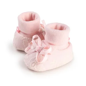 Close-up detail of cute pink baby socks with lace embroidery and satin bow