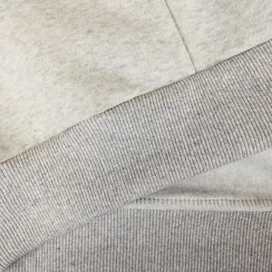 Vista macro del forro polar térmico y puño acanalado en la sudadera gris para hombre.