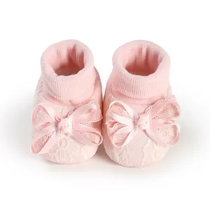 Close-up of soft pink baby girl lace socks with elegant ribbon bows for newborns