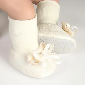 Close-up of adorable cream baby socks featuring delicate lace and silk bow details