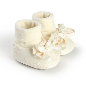 Close-up of elegant cream baby girl socks featuring lace pattern and large satin bow