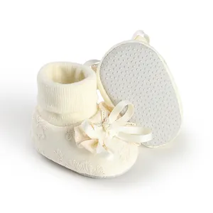 Close-up of cream baby girl socks featuring a decorative bow and non-slip rubber dots