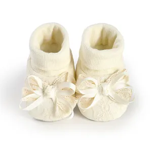 Detailed macro view of cream newborn baby girl socks with elegant lace and satin bow