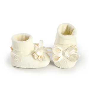 Detailed view of baby girl cream lace booties featuring delicate satin ribbon bows