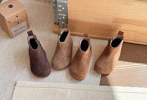 Gedetailleerd overzicht van retro suède enkellaarsjes voor kinderen in bruine tinten.