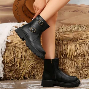 Detail showing black platform Martin boot on model's foot with rustic straw background