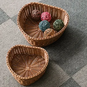 Two brown heart-shaped woven rattan style baskets for fruit and snacks on a carpet