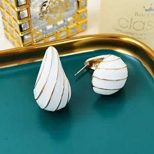 Nahaufnahme der eleganten weißen Emaille-Ohrringe mit goldenen Streifen im Wassertropfen-Stil