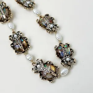 Dettaglio della collana vintage con perle e scarabei con conchiglia iridescente.