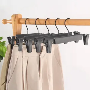 Détail de cintres à pinces noirs antidérapants pour pantalons sur portant en bois à domicile