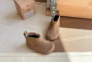 Vintage bruine suède laarzen voor kinderen gepresenteerd in een gezellige rustieke setting