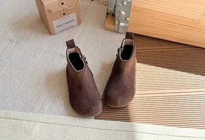 Detailweergave van bruine suède kinderlaarzen in retrostijl met ritssluiting in knusse sfeer