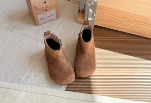 Hoogwaardige bruine suède enkellaarsjes voor kinderen met zijrits op een houten terras
