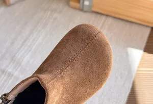 Gedetailleerde weergave van bruin suède materiaal en stiksels op vintage kinderlaarzen