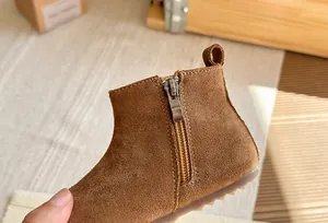 Detail van bruine suède kinderlaarzen met handige zijrits en een stevige profielzool.