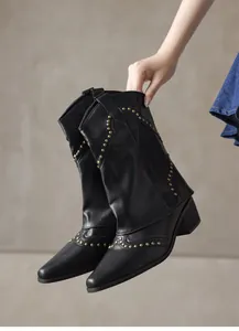 Detailed view of vintage black Western pointed-toe ankle boots with gold rivet studs.