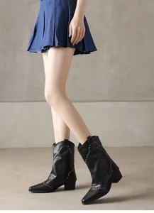 Detail shot of vintage black cowboy ankle boots featuring gold studs and a pointed toe
