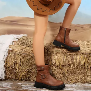Detail view of brown platform Martin boots with side buckles and zippers in a desert