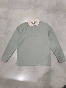 Vue détaillée du polo à manches longues vert sauge avec col beige contrasté