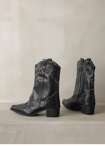 Close-up of black Western cowboy boots with gold rivet studs and pointed toe design