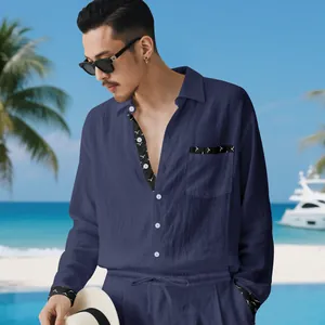 Asian male model posing in navy linen set against a tropical beach and yacht background.