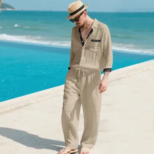 Full view of a man wearing a casual tan linen shirt and pants set by a sunny beach pool