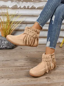 Detail van beige suède enkellaarzen met franjes en studs in westernstijl voor dames