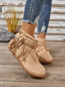 Stijlvolle beige suède enkellaarzen in westernstijl met franjes, gespen en studdetails.