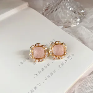 Macro view of vintage French enamel stud earrings featuring delicate pearl trim and gold finish.