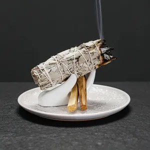 Witte keramische plaat met handhouder, brandende salie en Palo Santo-hout