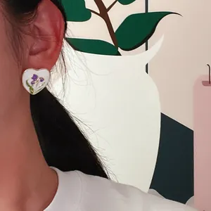 Primo piano di un orecchino vintage in smalto iris a forma di cuore all'orecchio