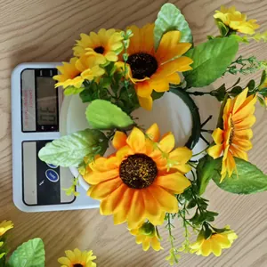 Detailed view of artificial sunflower candle ring wreath showing a weight of 30g on scale.