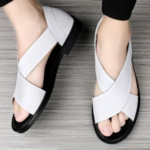 Gros plan de sandales en cuir blanc pour hommes avec brides croisées sur un sol en bois.