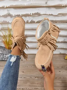 Detailopname van beige suède franjelaarzen in westernstijl met studs