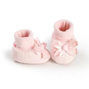 Close-up of pink baby socks with delicate lace floral pattern and cute bow detail