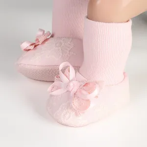 Close-up of pink baby girl anti-slip socks featuring elegant lace and a satin bow