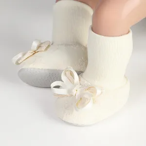 Detailed close-up of cream baby floor socks featuring a ribbon bow and non-slip sole