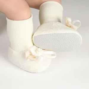 Detail of cream baby shoe-socks with a satin bow and non-slip rubber dot sole
