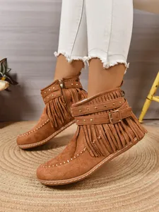 Detailopname van bruine suède westernlaarzen voor dames met franjes en metalen studs.