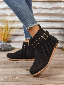 Detail van zwarte suède western laarzen met franjes, gesp en gouden studs decor