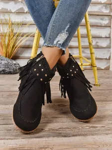 Gedetailleerd overzicht van zwarte western franjelaarzen voor dames met gouden studs.