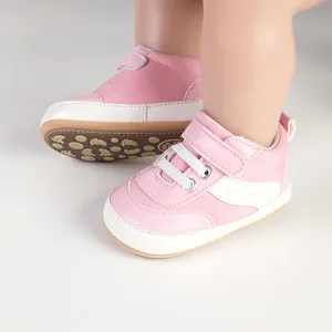 Detail view of pink baby walking shoes with white canvas and velcro straps.